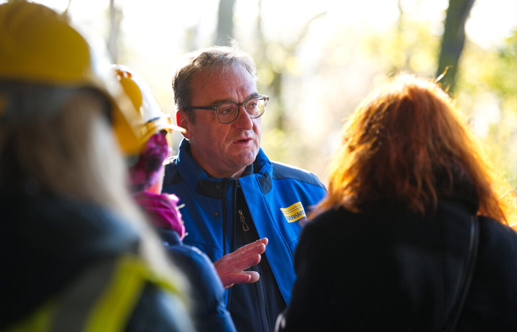 Nahaufnahme eines männlichen Gesichts im Profil mi weiteren Personen von hinten