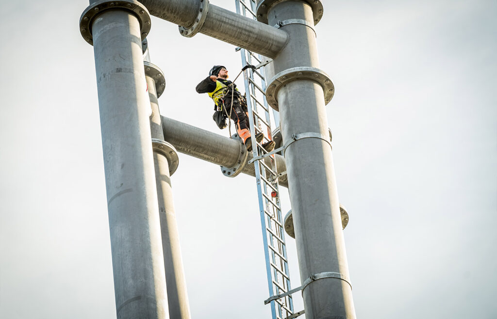 Arbeiter steht auf einer Leiter am Pylon der Neckarline