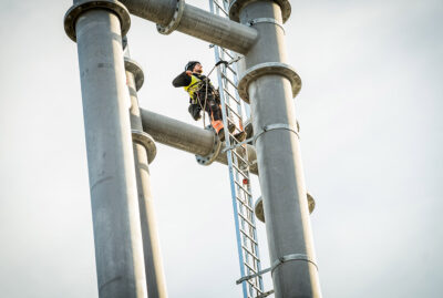 Arbeiter steht auf einer Leiter am Pylon der Neckarline