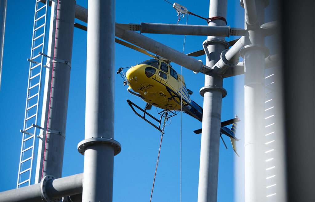 Eine Nahaufnahme eines fliegenden gelben Hubschraubers über Stahlstangen