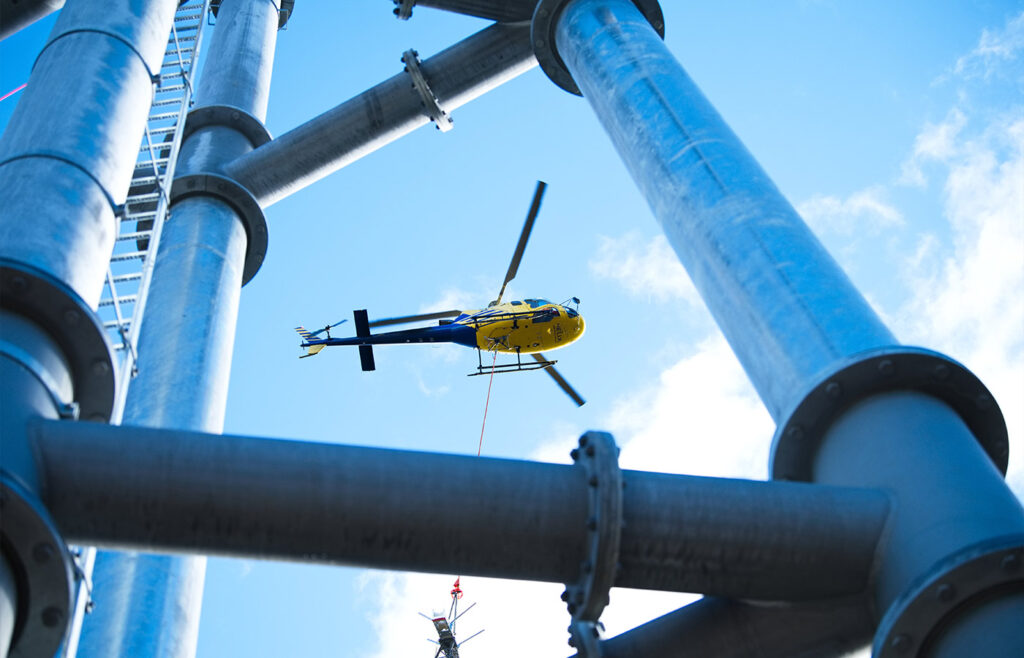 Ein fliegender gelber Hubschrauber über Stahlstangen