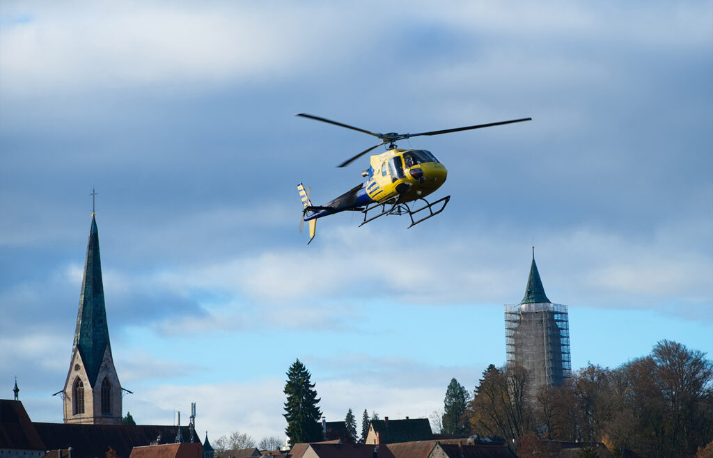 Ein fliegender gelber Hubschrauber über Hausdächern in der Luft