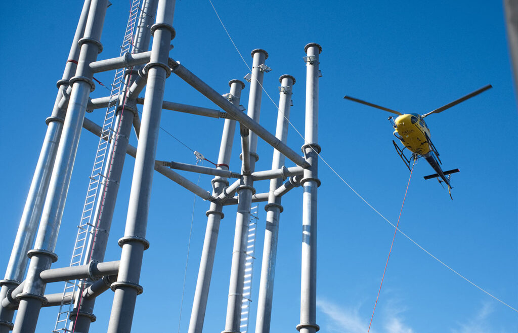 Ein fliegender gelber Hubschrauber neben Stahlstangen in der Luft