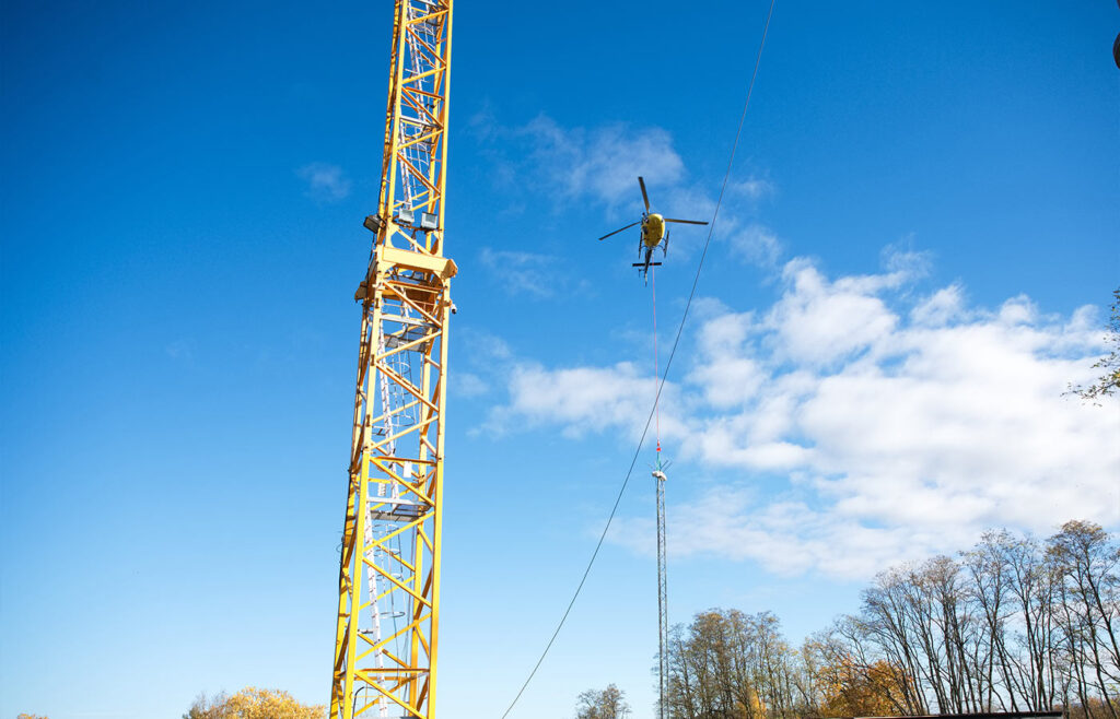 Ein fliegender gelber Hubschrauber neben einem gelben Kran in der Luft