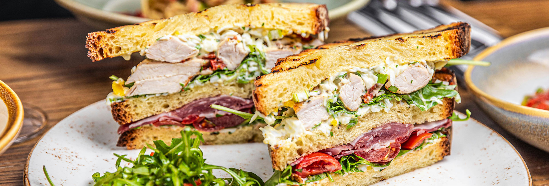 Nahaufnahme von zwei Pastrami-Sandwichs mit Salat auf einem Teller auf einem Holztisch