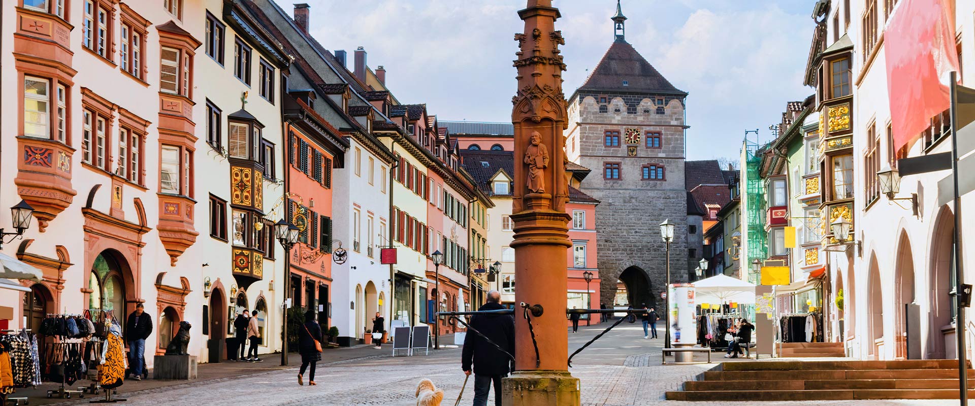 Ansicht auf historische Innenstadt mit Stadttor bei Sonnenschein mit Menschen und Geschäften