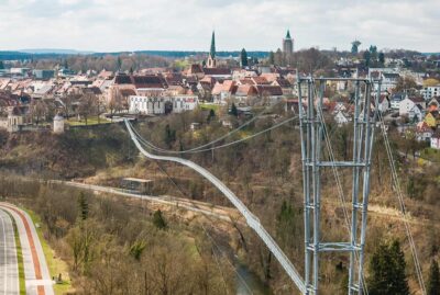 Abbildung einer Hängebrücke mit Altstadt im Hintergrund
