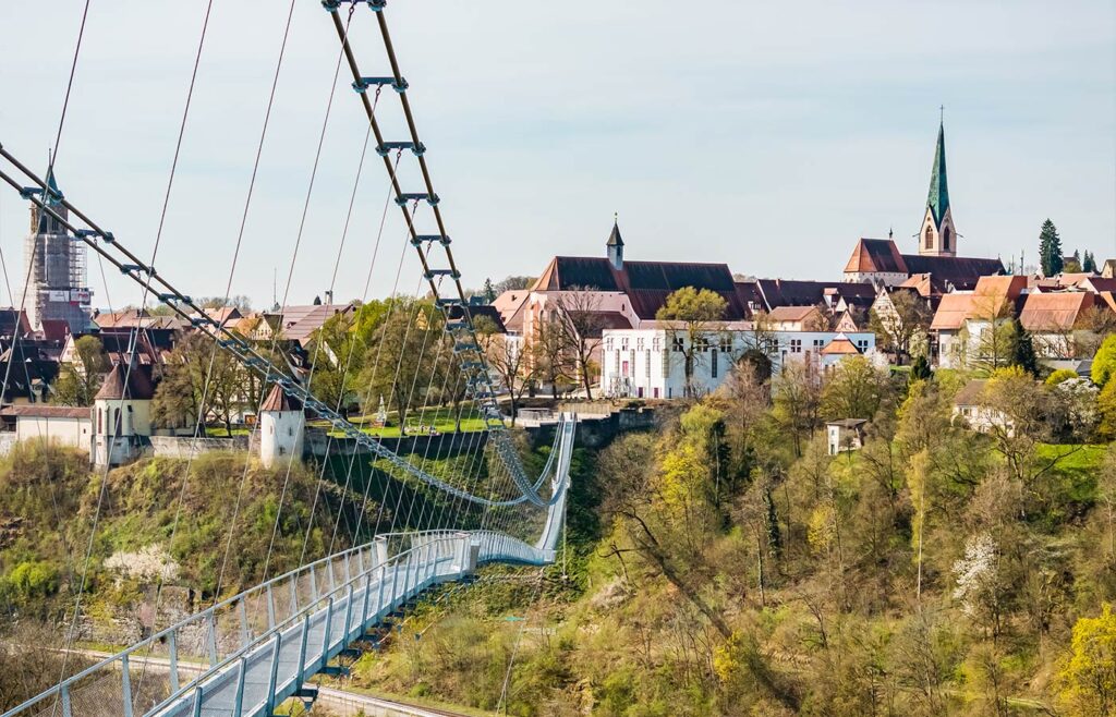 Abbildung einer Hängebrücke mit Altstadt im Hintergrund