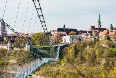 Abbildung einer Hängebrücke mit Altstadt im Hintergrund
