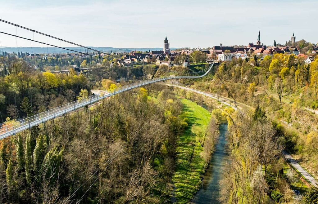 Abbildung einer Hängebrücke mit Altstadt im Hintergrund