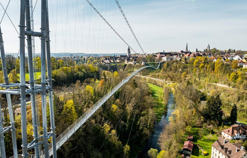 Abbildung einer Hängebrücke mit Altstadt im Hintergrund