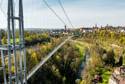 Abbildung einer Hängebrücke mit Altstadt im Hintergrund