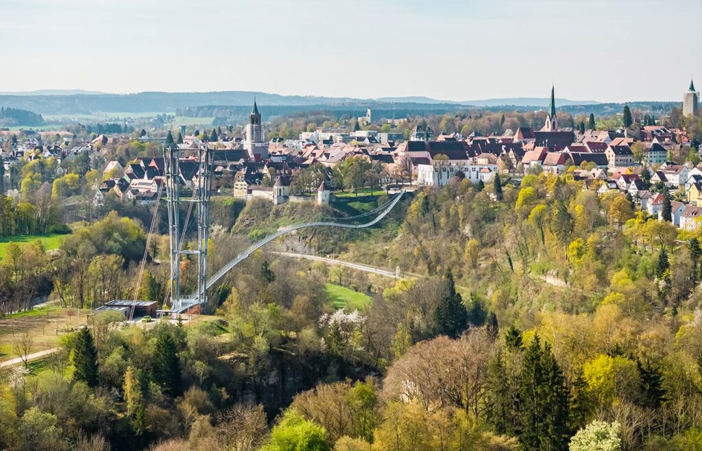 Abbildung einer Hängebrücke mit Altstadt im Hintergrund