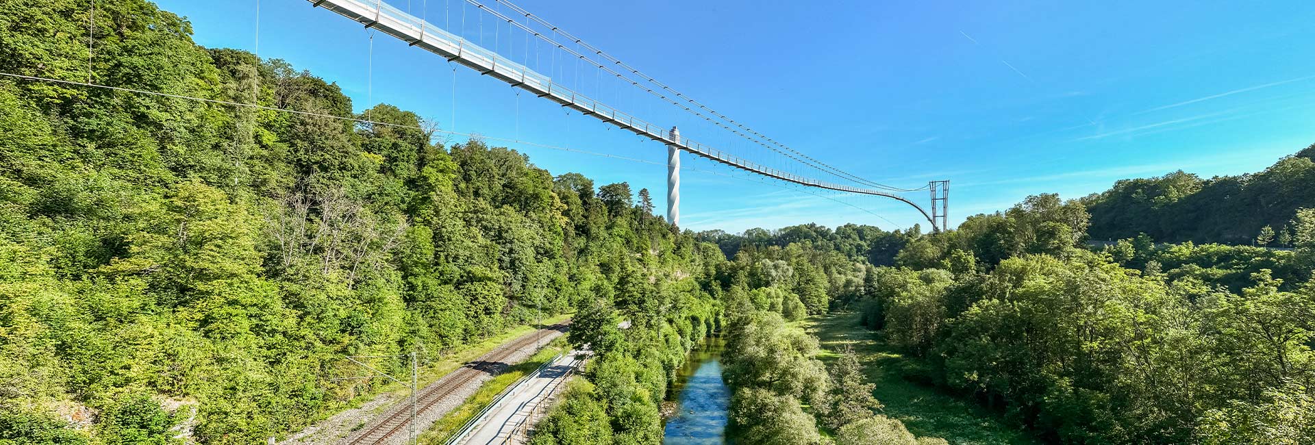 Sicht auf eine Hängebrücke von unten mit Turm im Hintergrund