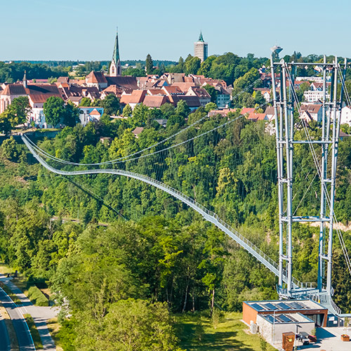 Abbildung einer Hängebrücke mit Altstadt im Hintergrund 
