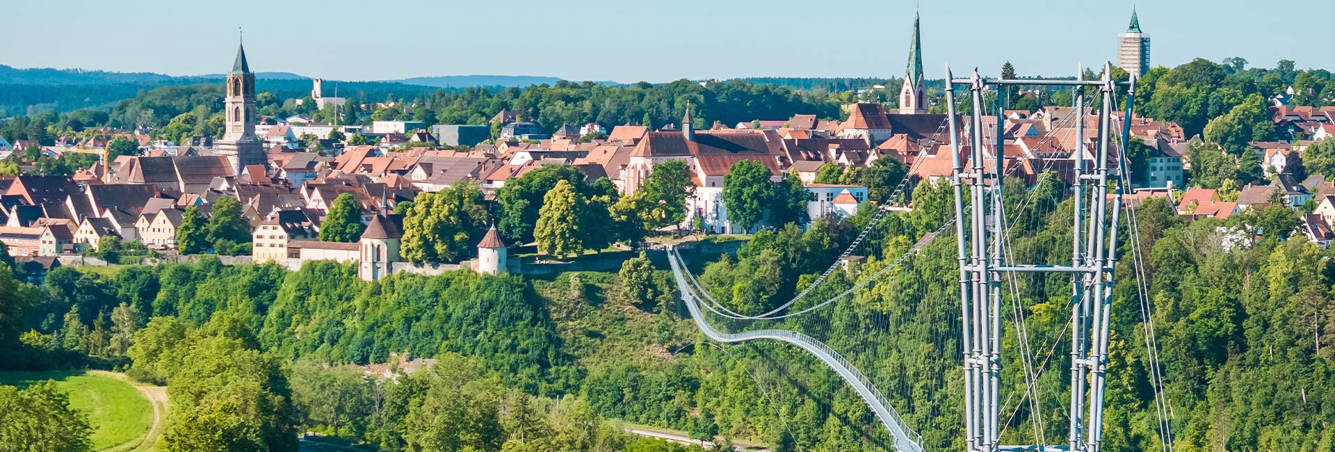 Abbildung einer Hängebrücke mit Altstadt im Hintergrund
