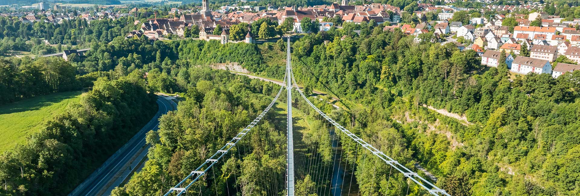 Sicht von oben auf eine Hängebrücke mit Altstadt im Hintergrund 